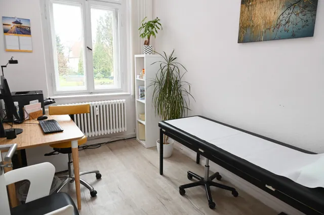 Behandlungszimmer mit Schreibtisch und Untersuchungsliege